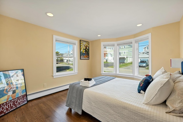 bedroom with dark hardwood / wood-style floors, multiple windows, and a baseboard heating unit