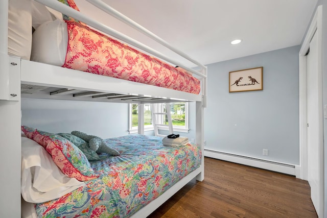 bedroom with dark hardwood / wood-style floors and a baseboard heating unit