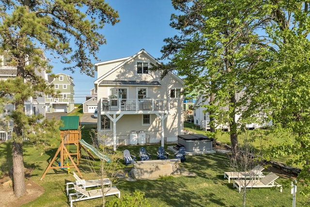 back of house with a balcony, a playground, a yard, and a hot tub