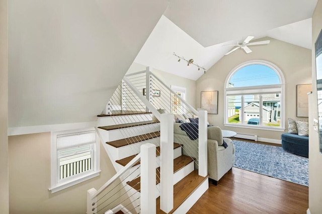 stairs featuring ceiling fan, wood-type flooring, lofted ceiling, and a baseboard heating unit