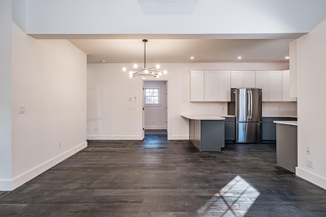 kitchen with pendant lighting, stainless steel fridge, a notable chandelier, dark hardwood / wood-style flooring, and white cabinetry