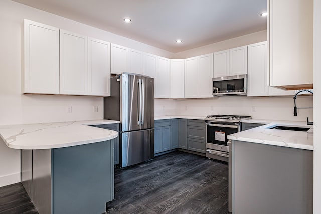 kitchen with kitchen peninsula, light stone counters, white cabinetry, and stainless steel appliances