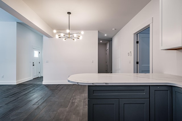 kitchen with light stone counters, dark hardwood / wood-style floors, pendant lighting, a chandelier, and white cabinets