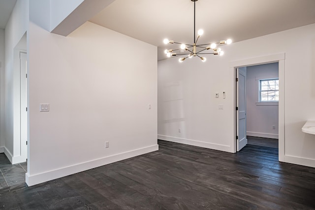 spare room with a chandelier and dark hardwood / wood-style floors