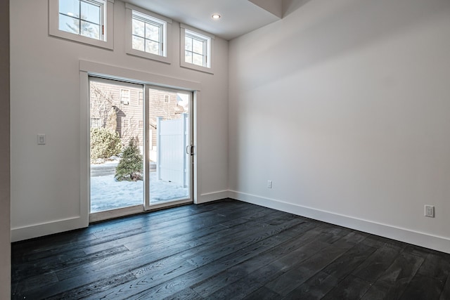 spare room featuring a towering ceiling and dark hardwood / wood-style floors