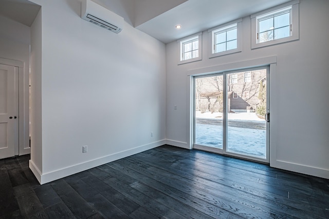 unfurnished room featuring a towering ceiling, a wall mounted AC, and dark wood-type flooring