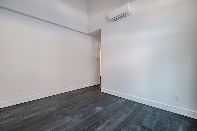 spare room featuring dark hardwood / wood-style floors, an AC wall unit, and a towering ceiling