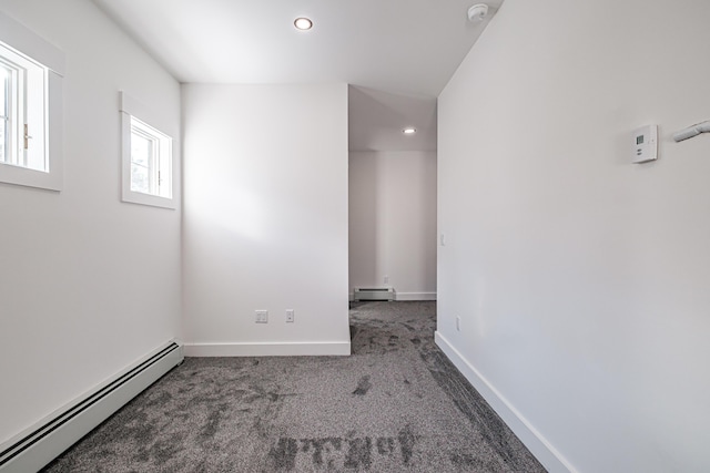 spare room featuring dark colored carpet and a baseboard radiator