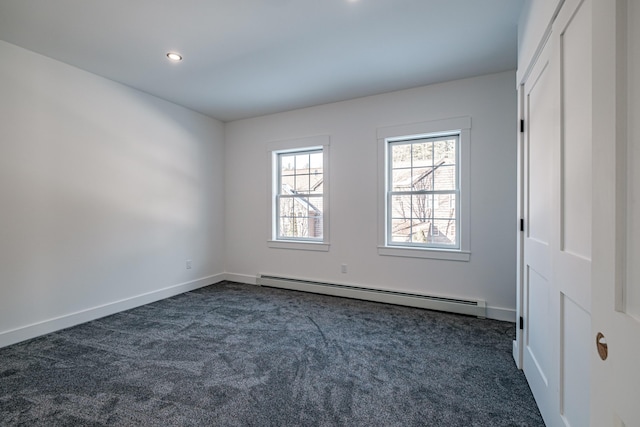 unfurnished room with baseboard heating and dark carpet