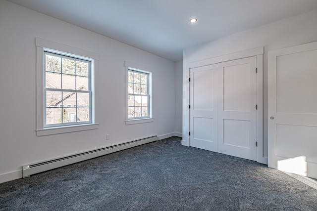 unfurnished bedroom featuring dark colored carpet, a baseboard radiator, and a closet