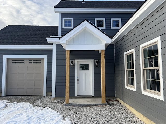 snow covered property entrance with a garage