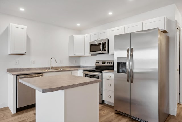 kitchen featuring sink, stainless steel appliances, a kitchen island, light hardwood / wood-style flooring, and white cabinets