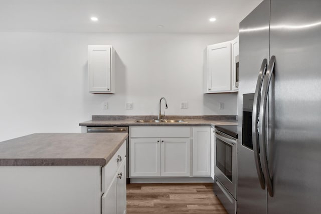 kitchen with hardwood / wood-style floors, sink, white cabinetry, and stainless steel appliances