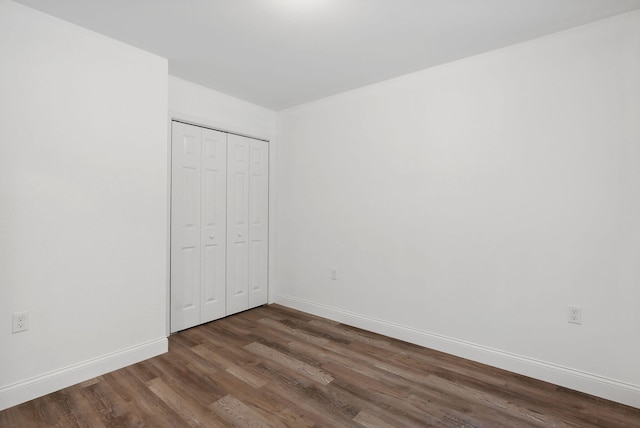 unfurnished bedroom with dark hardwood / wood-style flooring and a closet