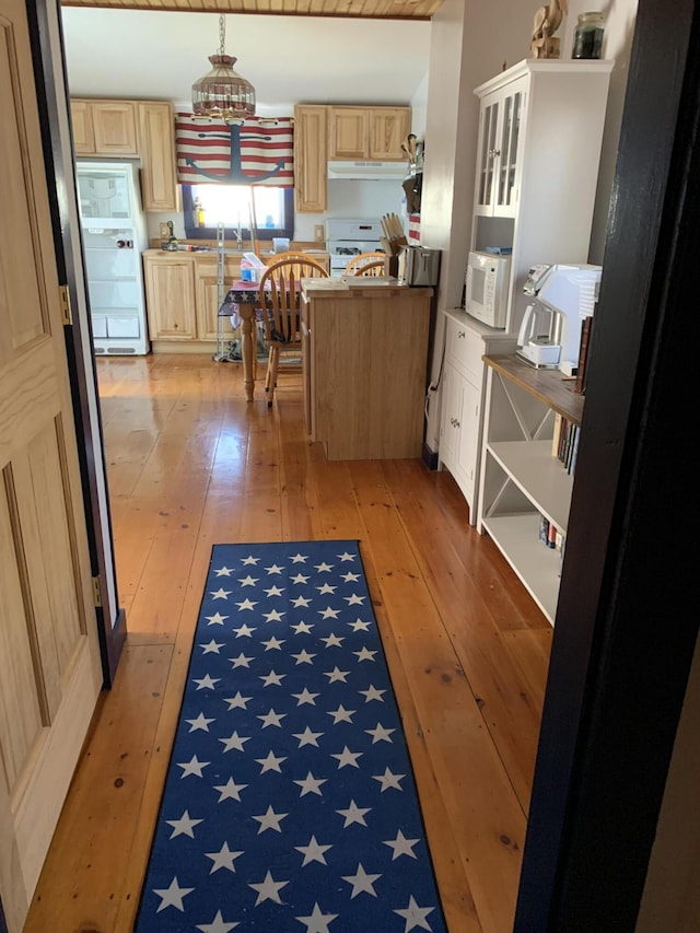 kitchen featuring light brown cabinets, white appliances, and light hardwood / wood-style flooring