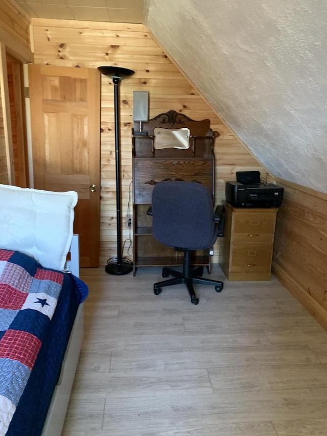 bedroom with light hardwood / wood-style floors and wooden walls