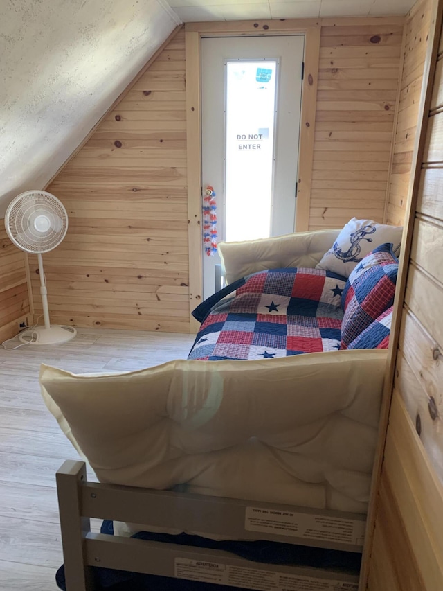 bedroom featuring lofted ceiling, hardwood / wood-style flooring, and wooden walls