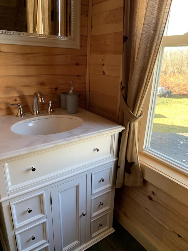 bathroom featuring wood-type flooring, vanity, a wealth of natural light, and wooden walls