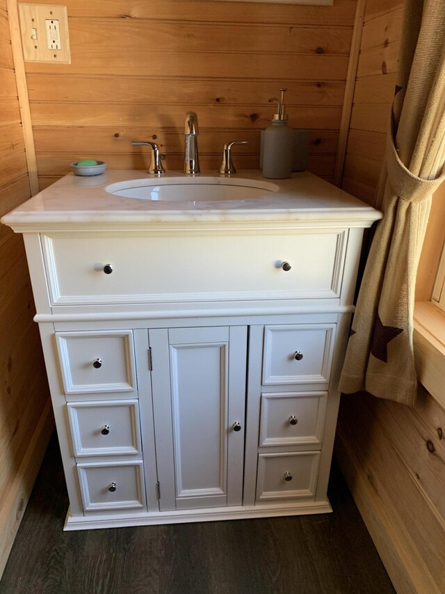 bathroom with vanity, hardwood / wood-style flooring, and wooden walls