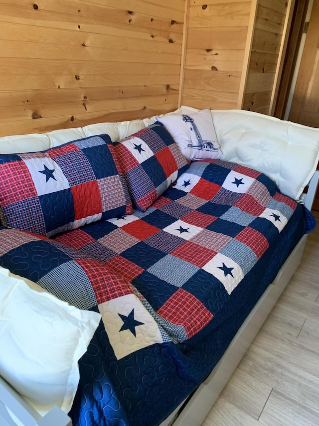 bedroom with hardwood / wood-style flooring and wood walls