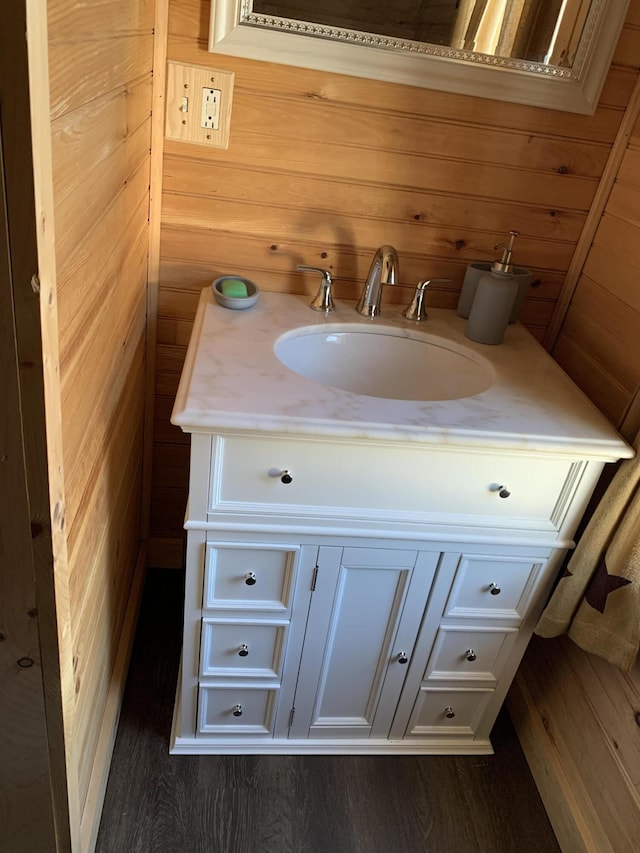 bathroom with vanity, wood walls, and wood-type flooring