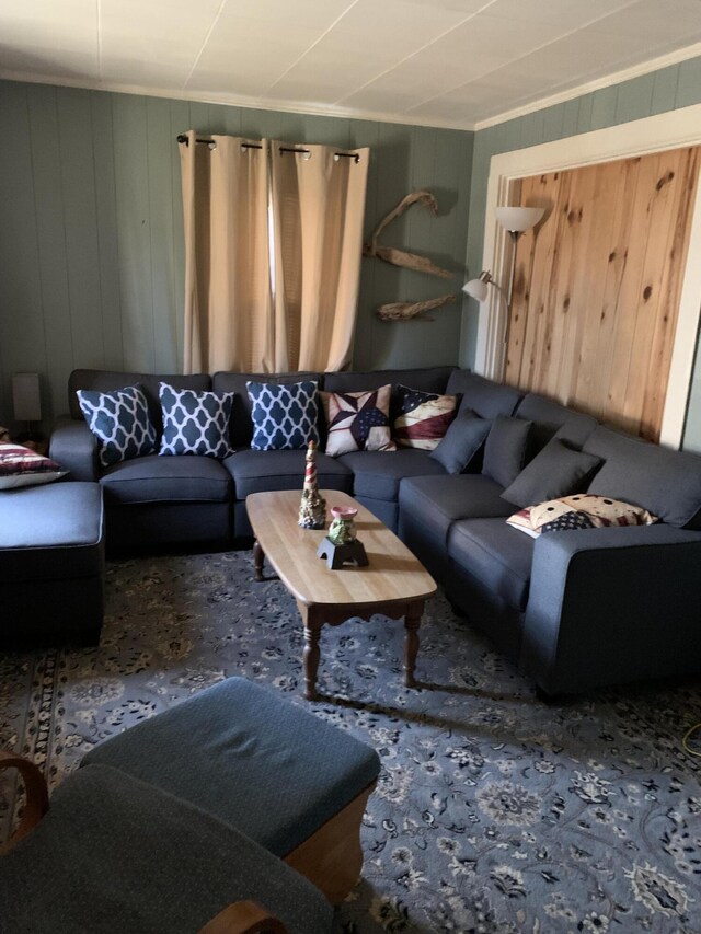 carpeted living room featuring ornamental molding and wood walls