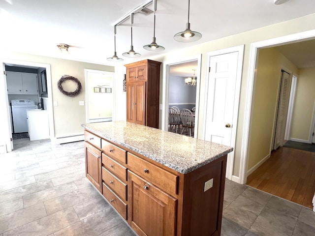 7 Edgewood Dr, Orono, ME 04473 - kitchen with washer / clothes dryer, baseboard heating, light stone countertops, decorative light fixtures, and a center island