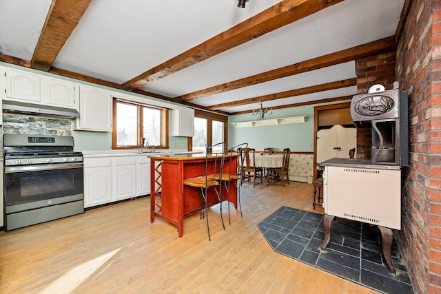 kitchen with white cabinetry, light hardwood / wood-style flooring, brick wall, extractor fan, and stainless steel range with gas stovetop