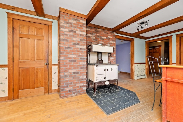 interior space with beam ceiling, a baseboard radiator, and light hardwood / wood-style flooring