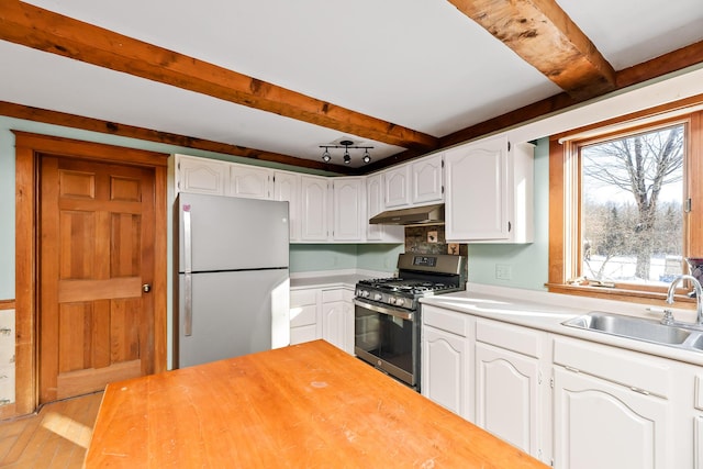 kitchen with sink, stainless steel appliances, light hardwood / wood-style flooring, beamed ceiling, and white cabinets