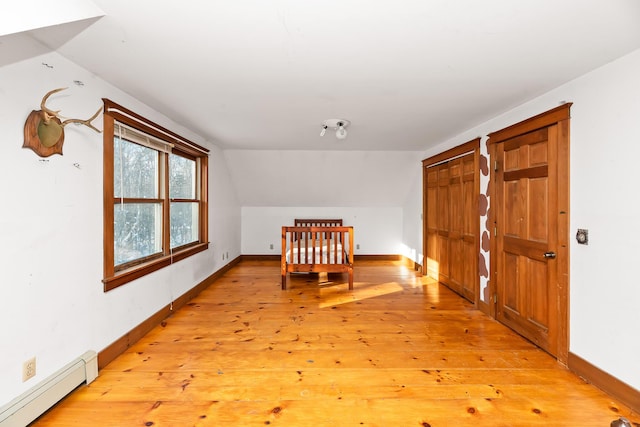 bonus room with lofted ceiling, light wood-type flooring, and a baseboard radiator