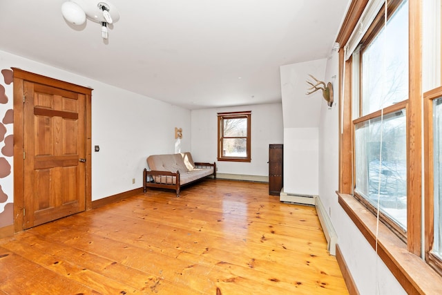 unfurnished room featuring light wood-type flooring and baseboard heating