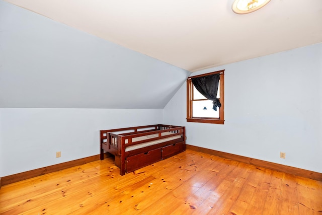 additional living space with light hardwood / wood-style floors and lofted ceiling