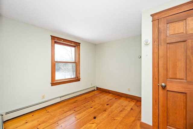 spare room with baseboard heating and light wood-type flooring