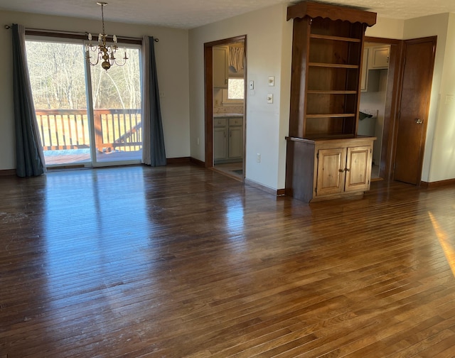 unfurnished living room featuring dark hardwood / wood-style floors and an inviting chandelier