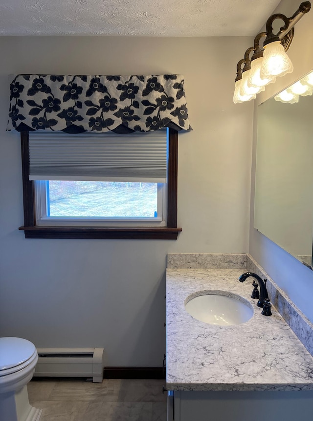 bathroom with baseboard heating, vanity, a healthy amount of sunlight, and a textured ceiling