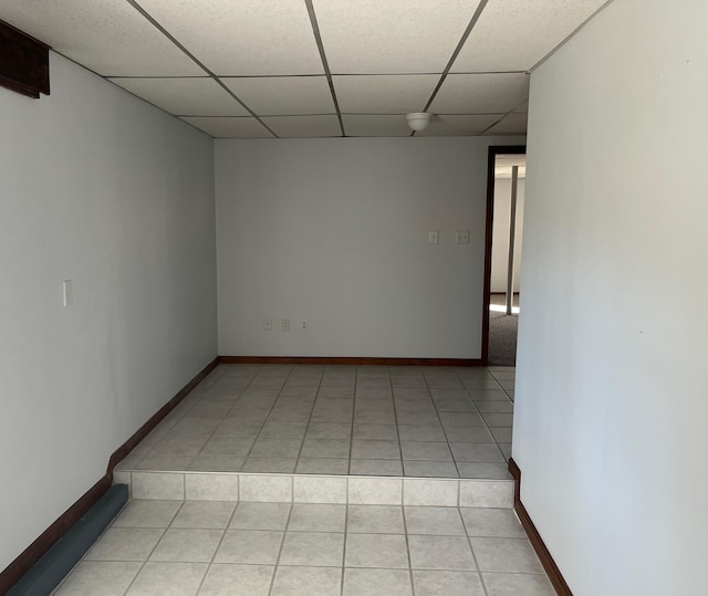 tiled empty room featuring a paneled ceiling