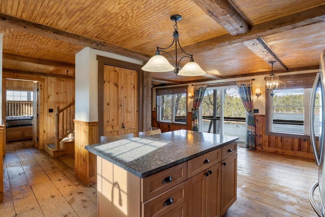 kitchen featuring wooden walls, light hardwood / wood-style flooring, a kitchen island, and hanging light fixtures