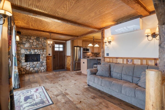 living room featuring beamed ceiling, a fireplace, wooden walls, and light hardwood / wood-style flooring