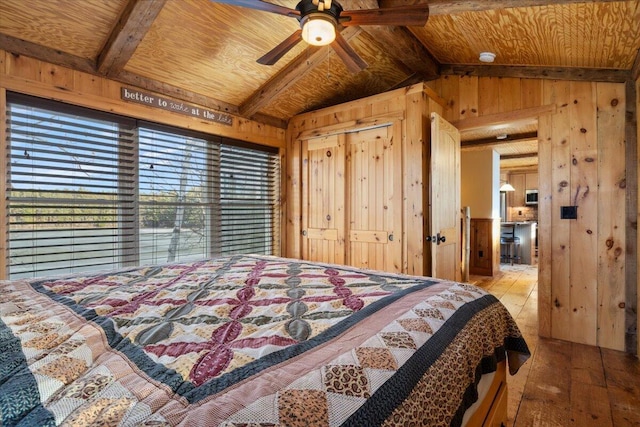 bedroom with wooden walls, hardwood / wood-style flooring, vaulted ceiling with beams, ceiling fan, and wood ceiling