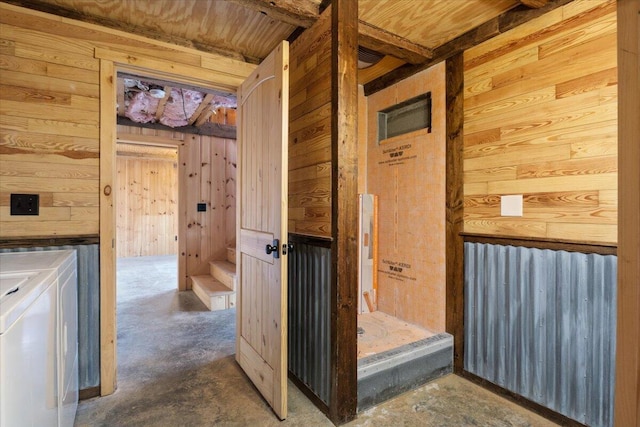 bathroom with washer and dryer, concrete flooring, and wooden walls