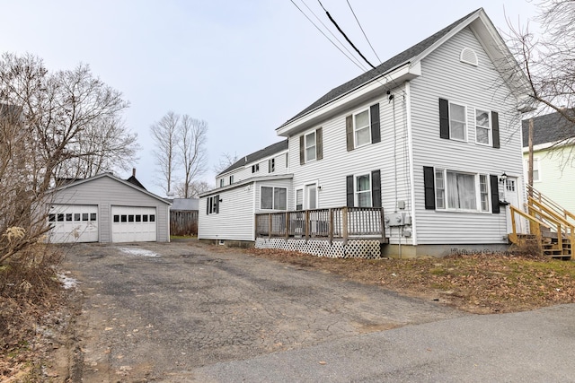 view of property exterior with a wooden deck, an outbuilding, and a garage