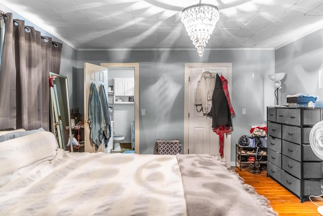 bedroom with hardwood / wood-style flooring, ensuite bath, crown molding, and a chandelier