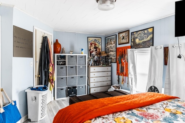 bedroom featuring hardwood / wood-style flooring, ornamental molding, and a closet