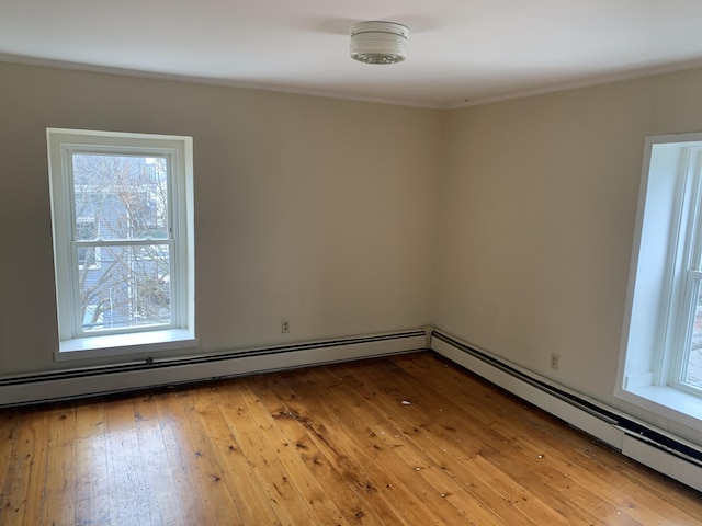 empty room with light hardwood / wood-style floors and a baseboard heating unit