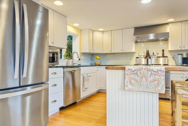 15 Brentwood Dr Unit 4, Cumberland, ME 04110 - kitchen with wall chimney range hood, light wood-type flooring, stainless steel appliances, and tasteful backsplash