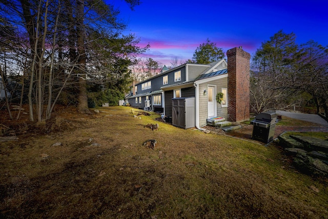15 Brentwood Dr Unit 4, Cumberland, ME 04110 - property exterior at dusk with metal roof, entry steps, a chimney, a lawn, and a standing seam roof
