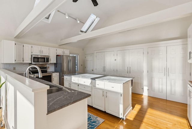 kitchen featuring white cabinetry, appliances with stainless steel finishes, a center island, and dark stone counters