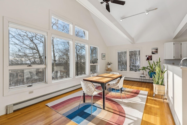 sunroom / solarium featuring rail lighting, lofted ceiling, and baseboard heating