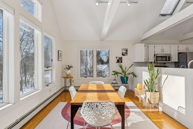 dining space with vaulted ceiling with beams, baseboard heating, and light hardwood / wood-style floors